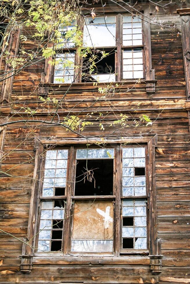 Abandoned wooden house with broken windows, boarded up doors, and overgrown with ivy. photo