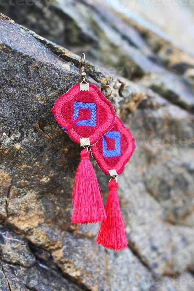 Red and blue earrings from threads hangs on a stones. Handmade jewelry. photo