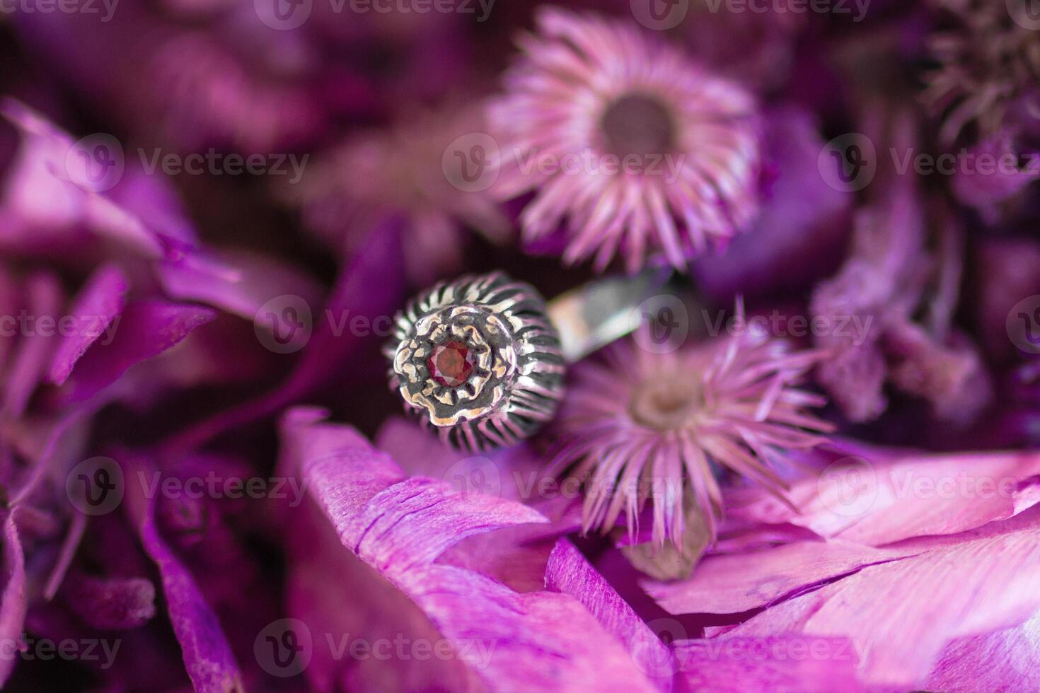 Beautiful silver ring with pink stone on a background of dry purple flowers. Handcraft precious item. photo