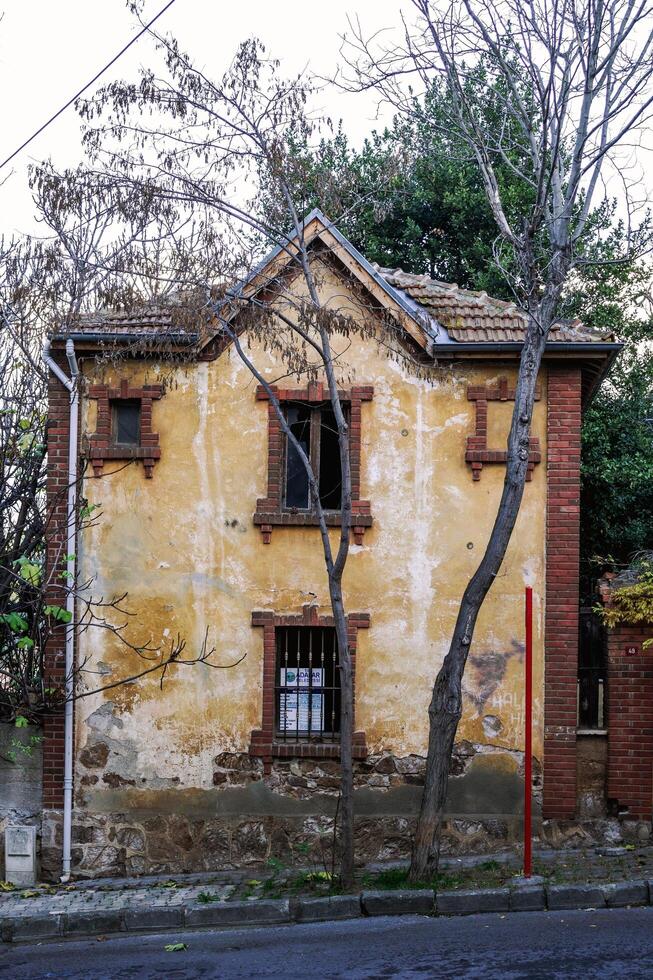 Istanbul, Turkey - January 06, 2023. Weathered yellow exterior of an old abandoned house with boarded-up windows. photo