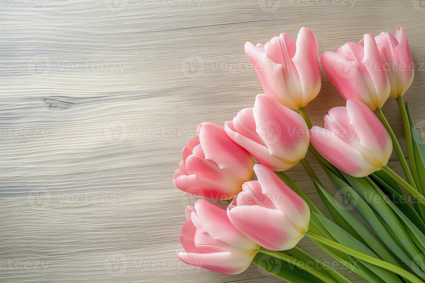 A bouquet of pink tulips is arranged on a wooden table photo