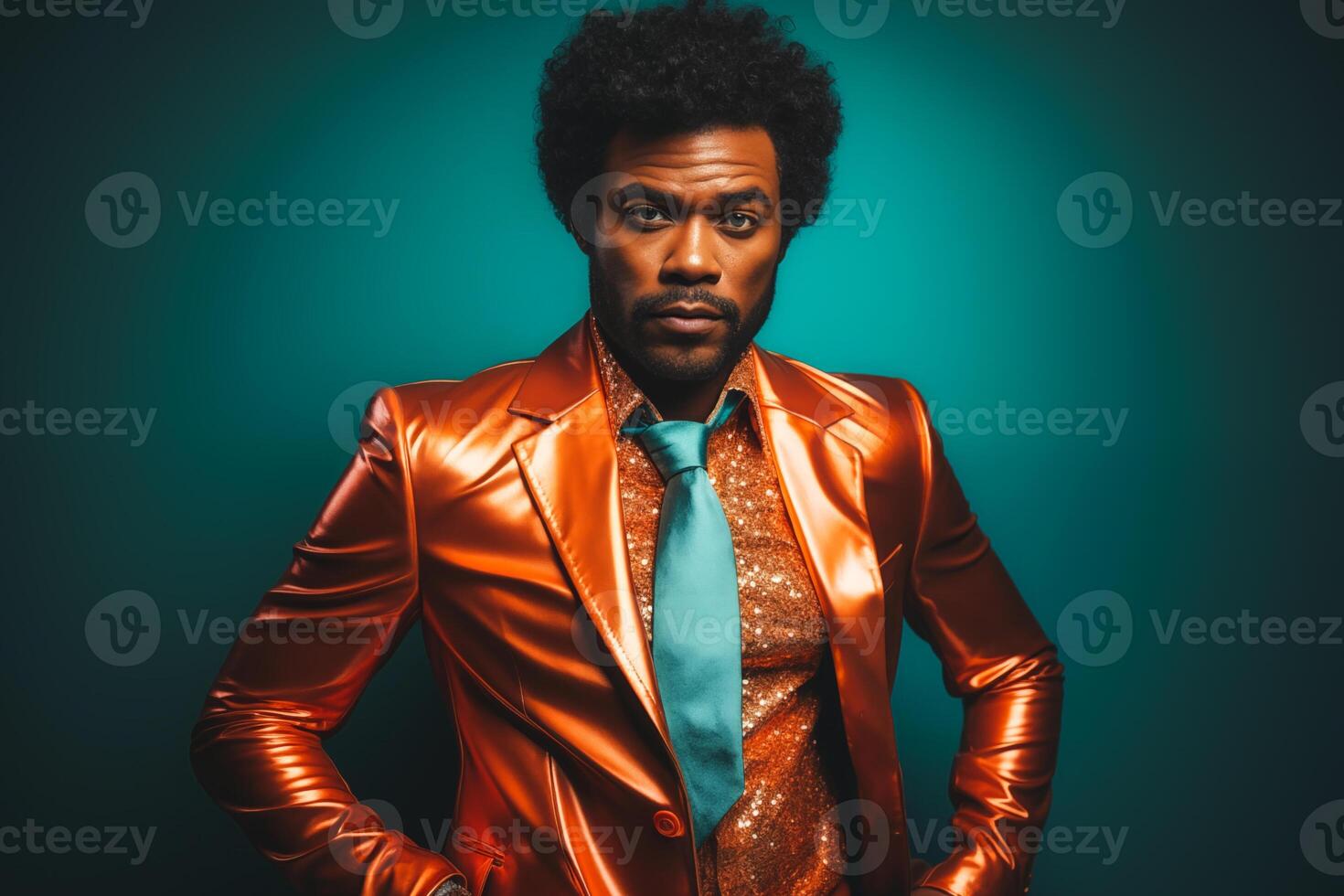 Trendy young man with afro posing in a vibrant orange leather jacket against a teal background photo