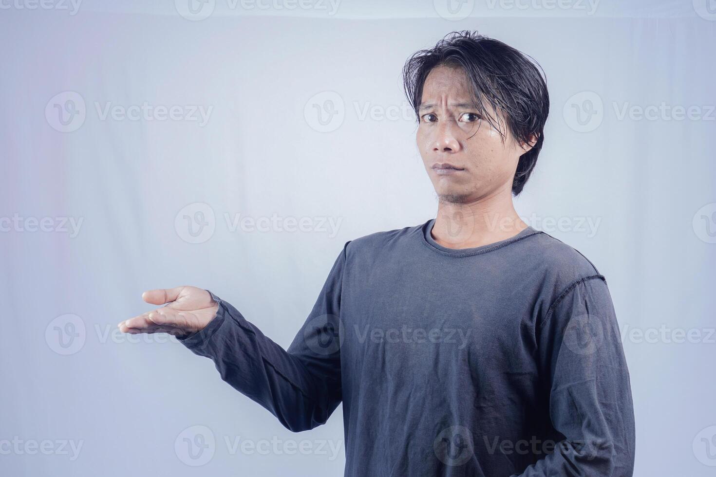 Handsome Asian man facing the camera is pointing at the copy space for advertising on an isolated white background. photo