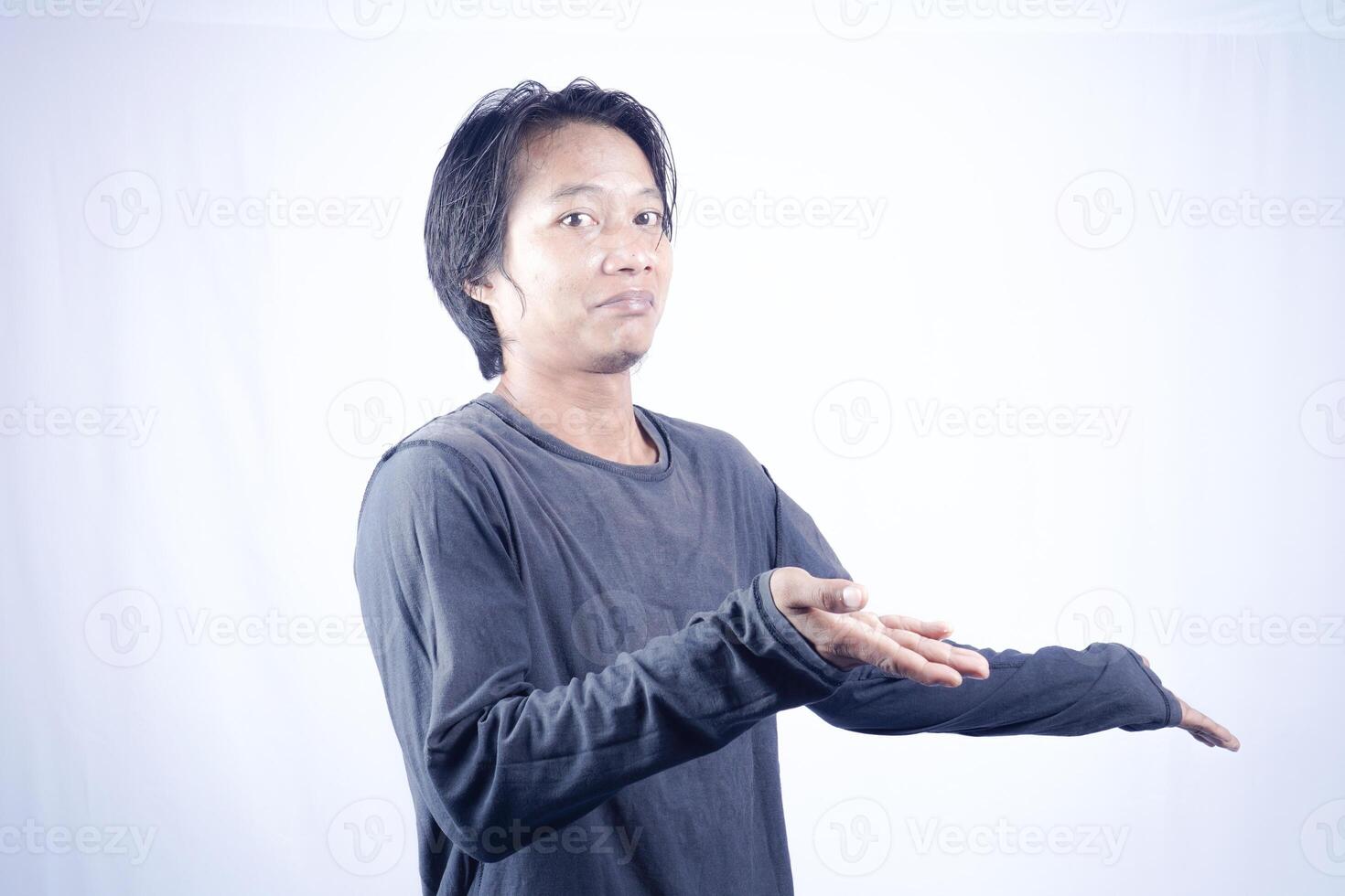 Handsome Asian man facing the camera is pointing at the copy space for advertising on an isolated white background. photo