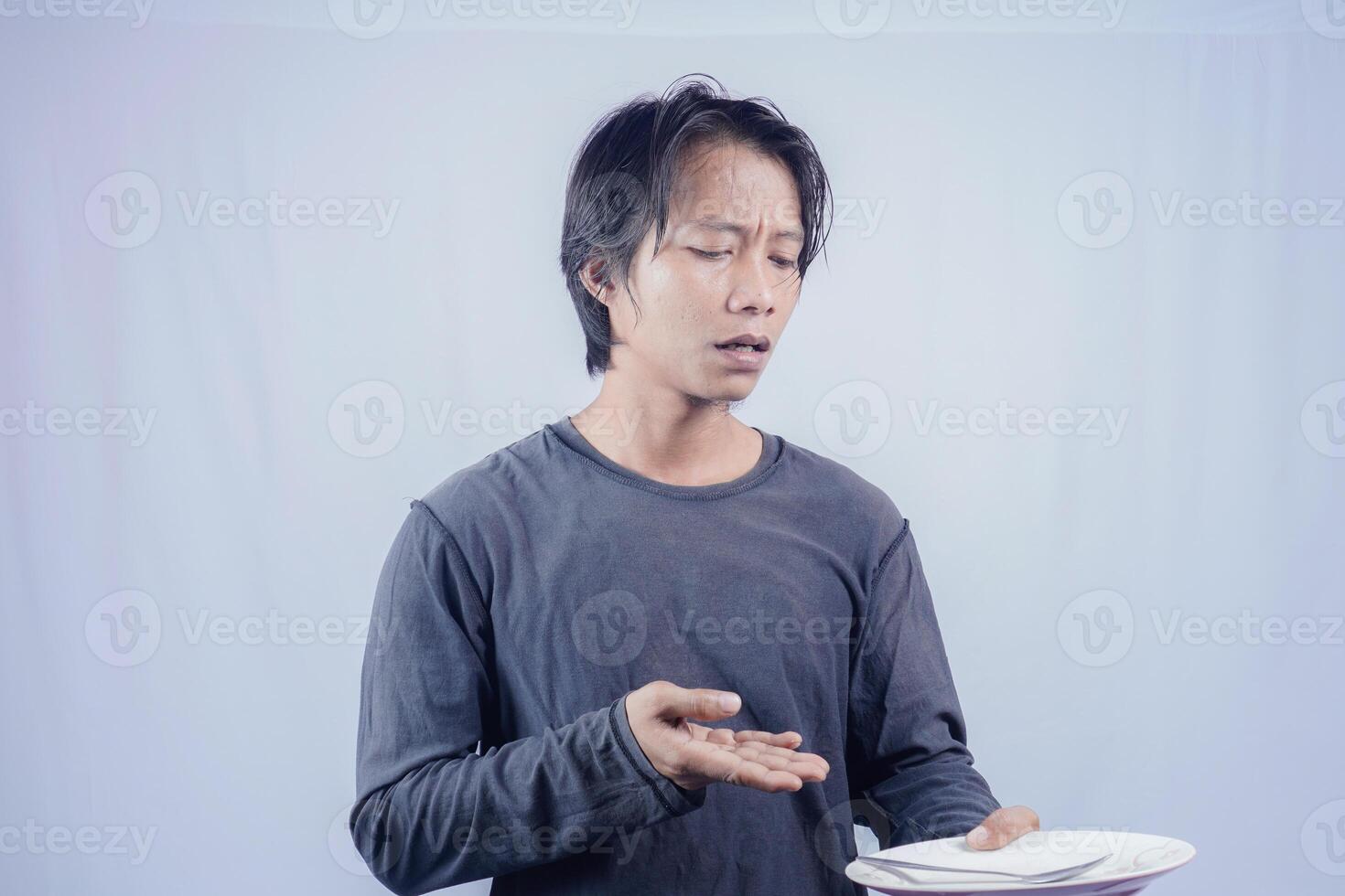 Handsome Asian man is pointing at an empty plate with a gloomy expression, isolated white background for advertising photocopy. photo