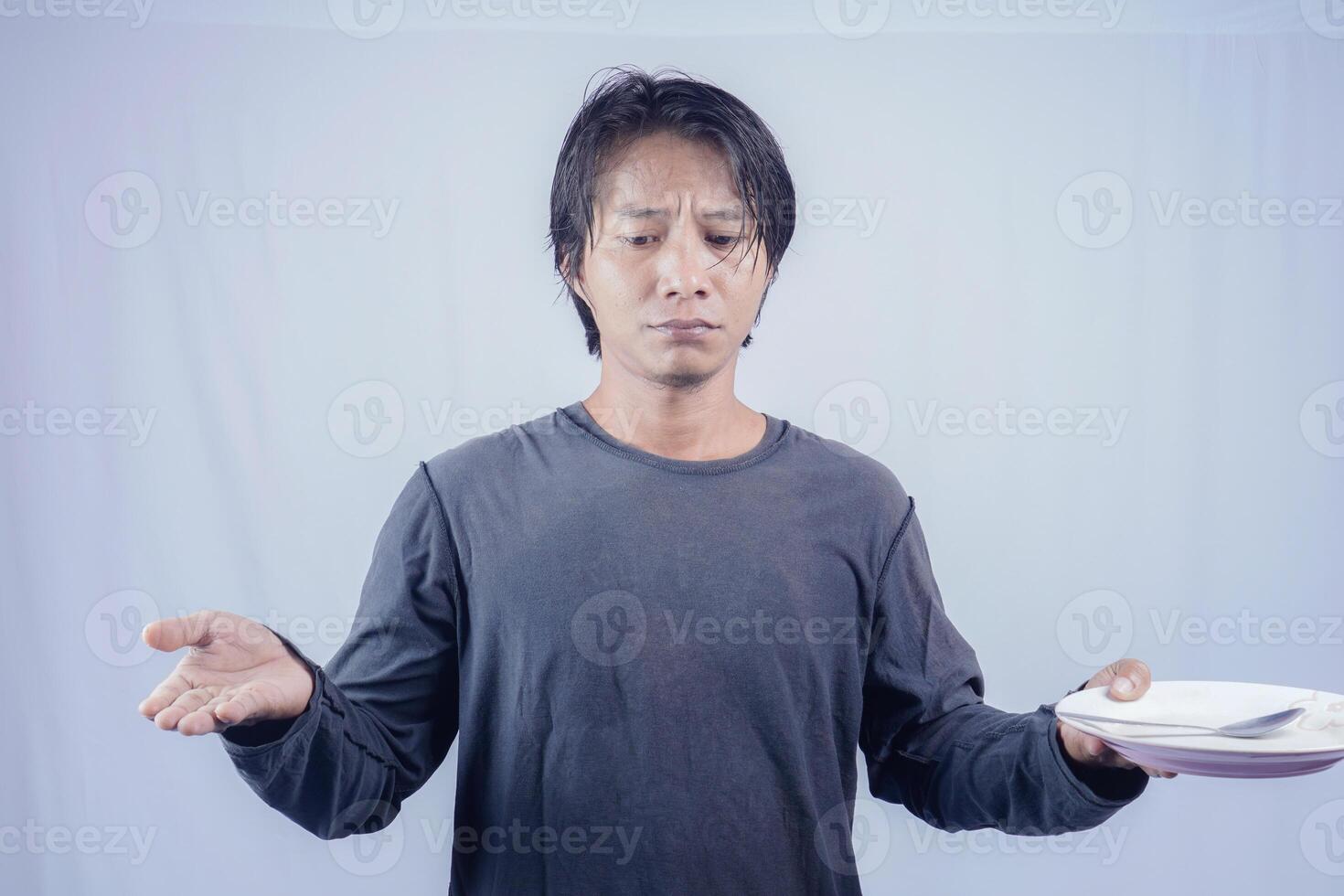 Handsome Asian man is pointing at an empty plate with a gloomy expression, isolated white background for advertising photocopy. photo