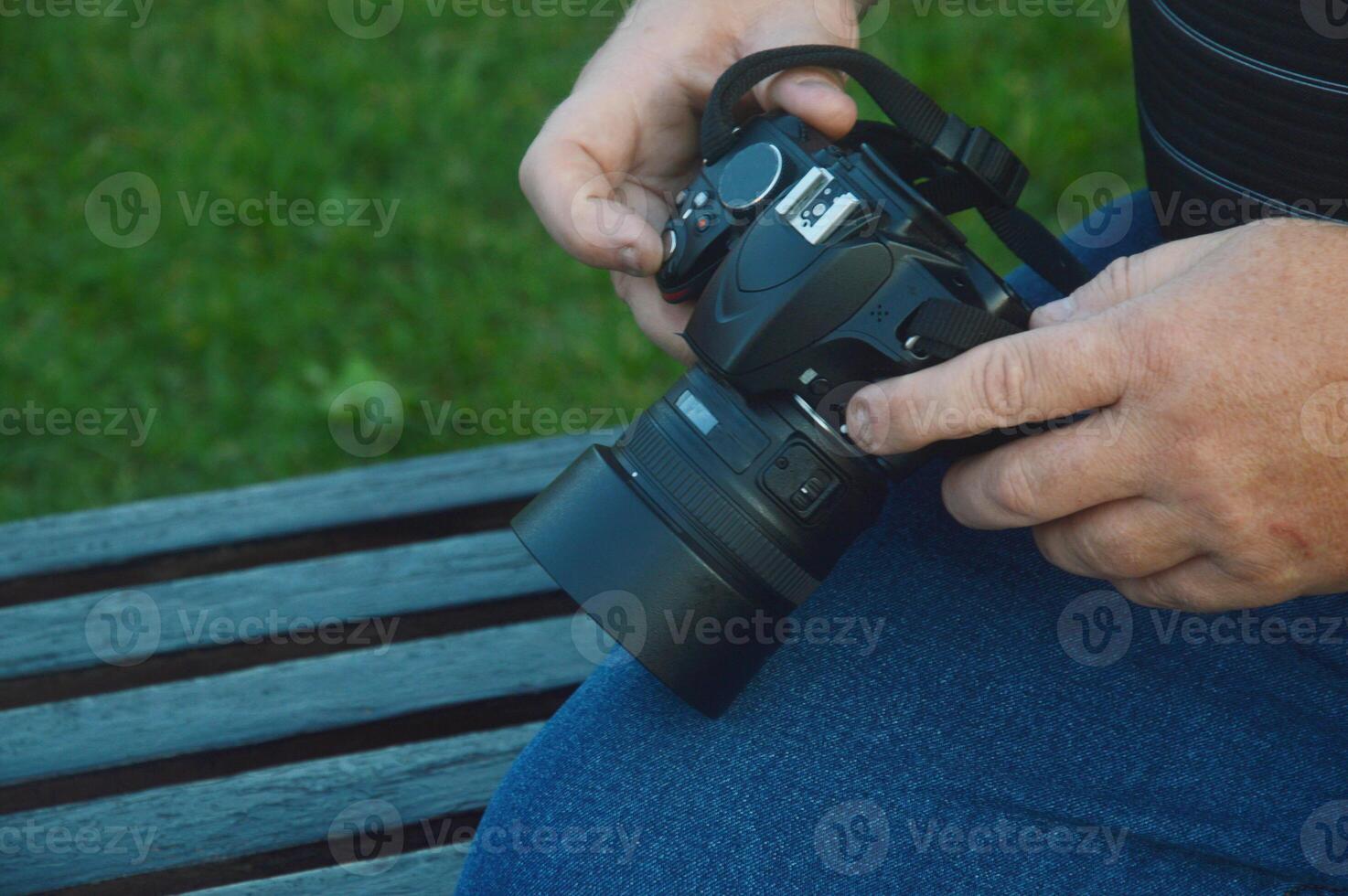 A male photographer with a modern camera in his hands sits on a bench and looks through pictures. photo