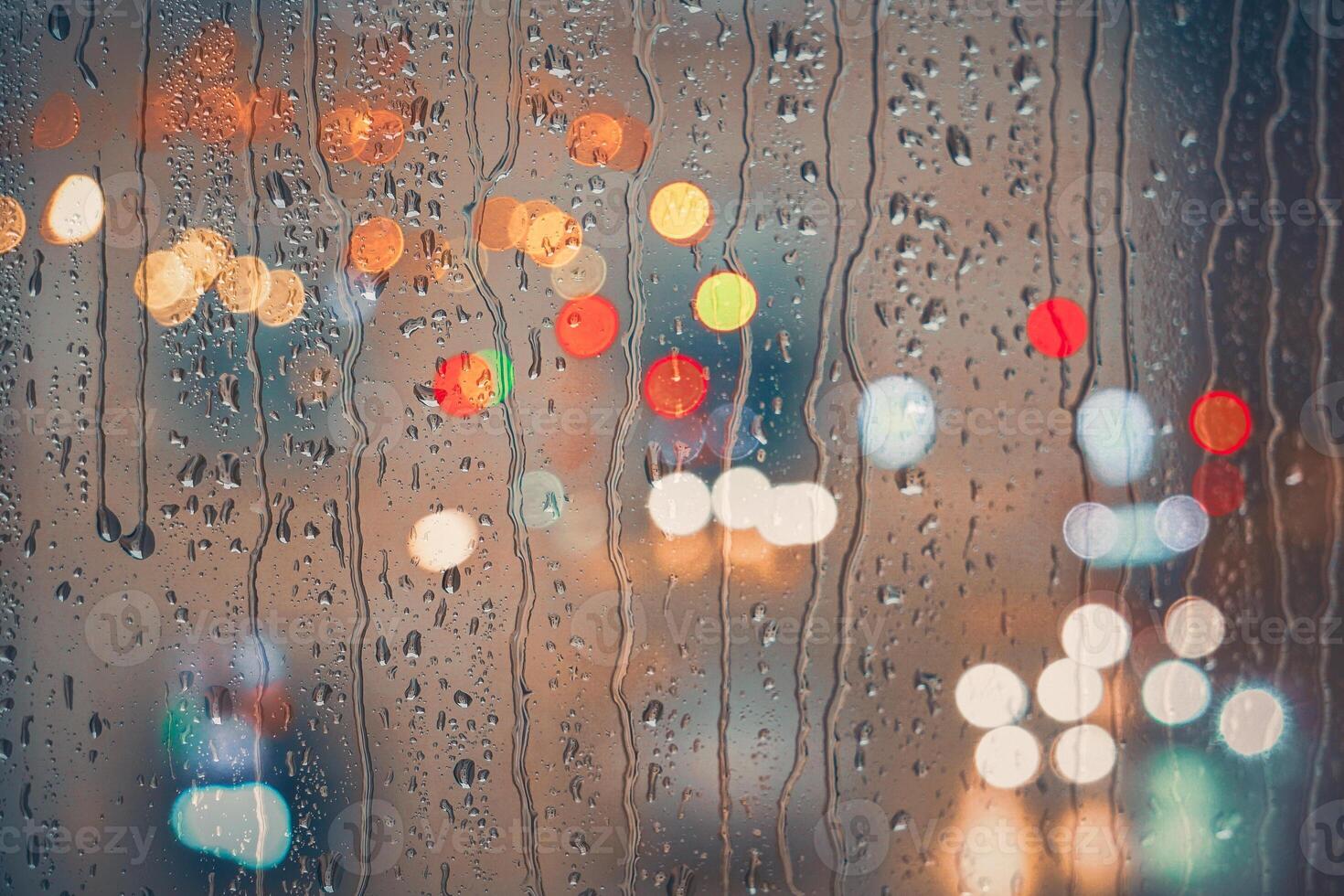 raindrops on the window and multi colored street lights at night background photo