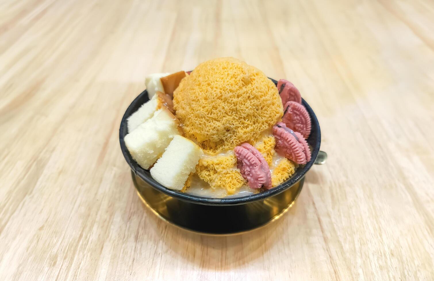 tailandés Leche té bingsu afeitado hielo en coreano estilo con galletas y pastel coberturas en negro taza en de madera mesa parte superior a café foto