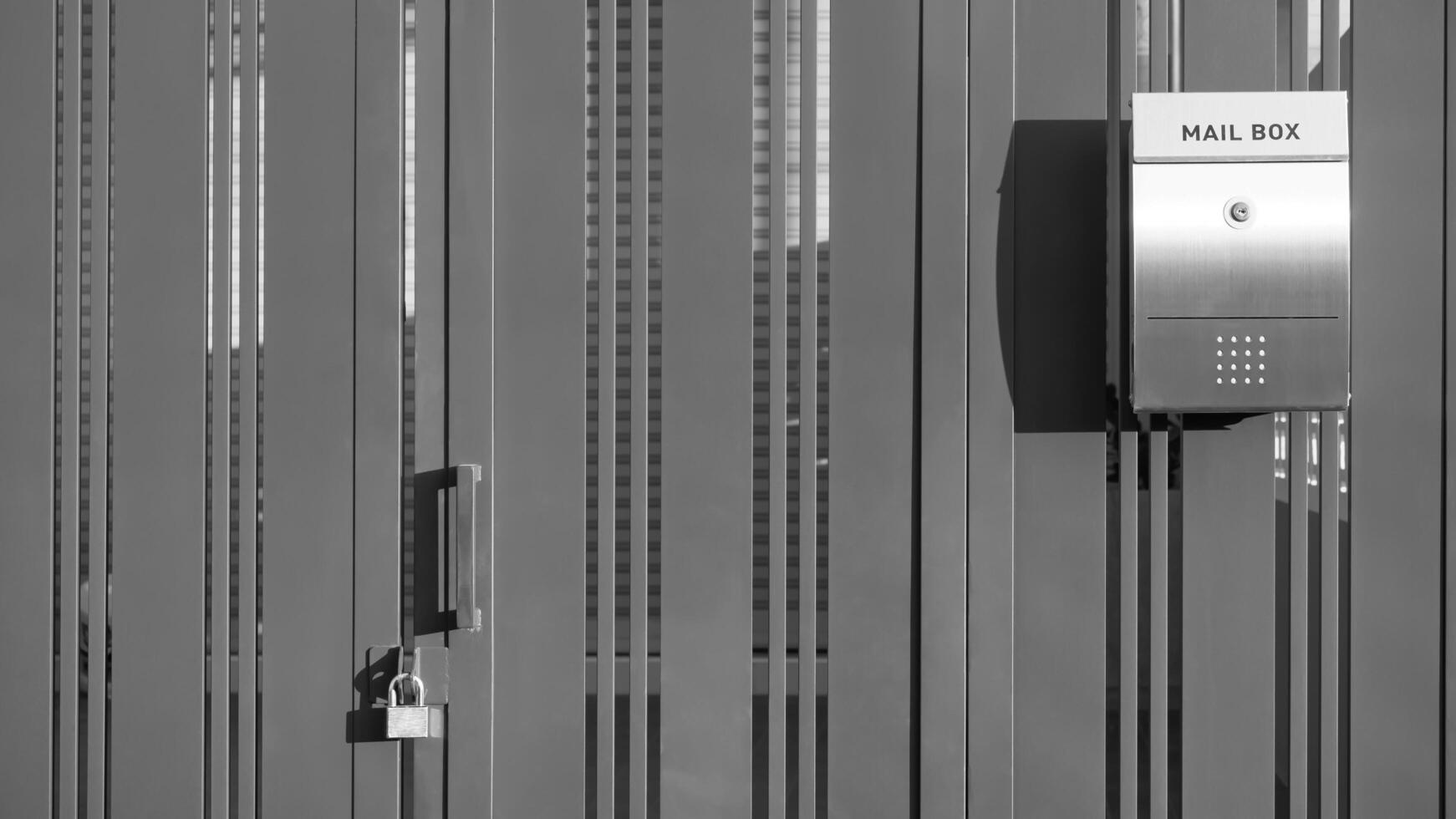 Stainless steel mailbox on aluminium folding gate door in front of modern house in black and white style, exterior architecture background photo