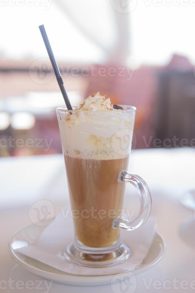 café es servido en un alto vaso vaso con un paja. el concepto de café bebidas desde el bar menú foto