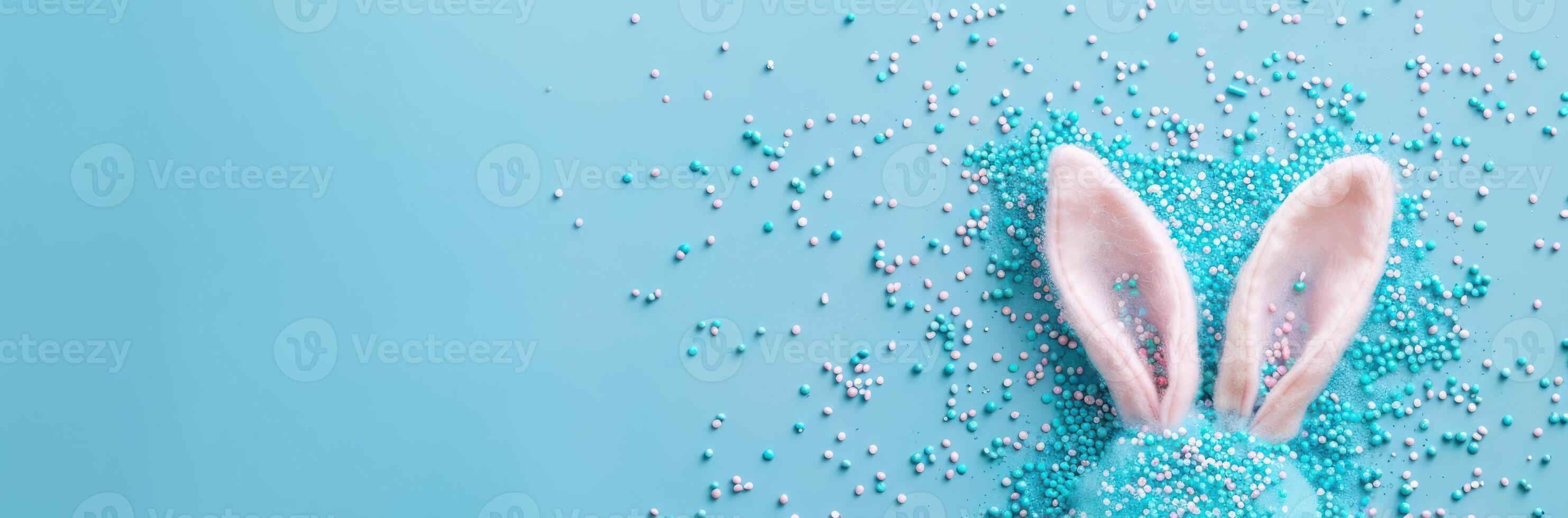 top view of adorable bunny ears and a sprinkle of confetti on a pastel blue backdrop photo