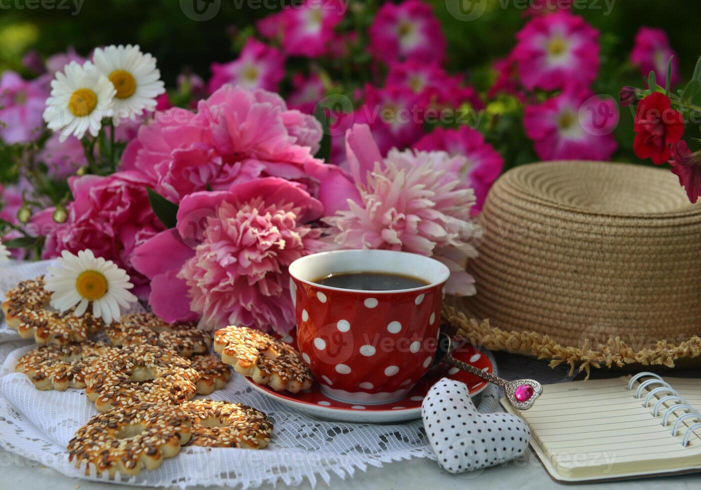 Beautiful still life with peony flowers, vintage cup and cookies on the table. Romantic greeting card for birthday, Valentines, Mothers Day concept. Summer background with vintage objects photo