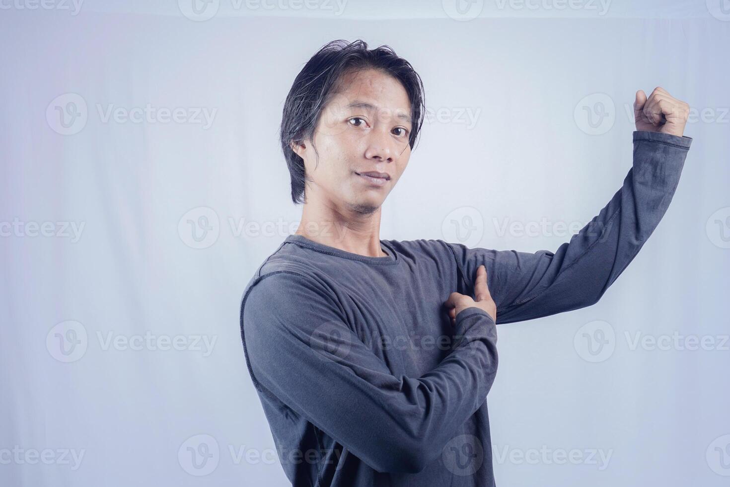 handsome asian man is cheering with raised hand to show his arm strength on isolated white background for copy space photo