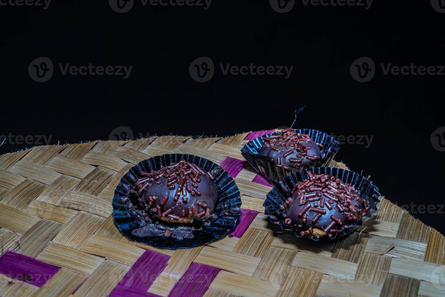 Isolated chocolate dumplings, close-up view of chocolate dumplings sprinkled with sprinkles, with woven bamboo as a base. Eid meal concept. photo