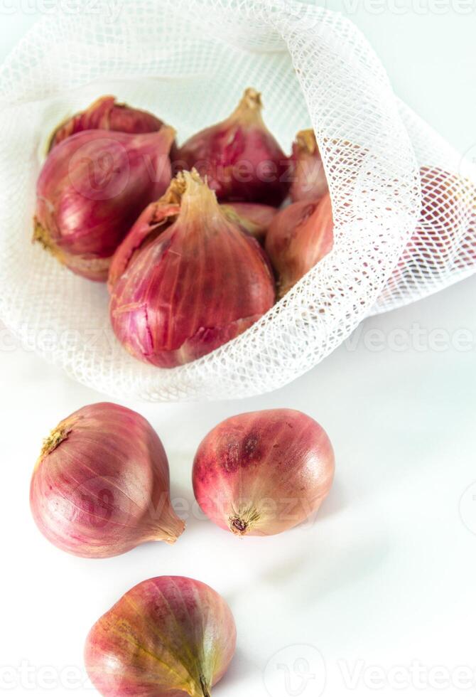 rojo cebollas en malla bolso aislado en blanco antecedentes foto