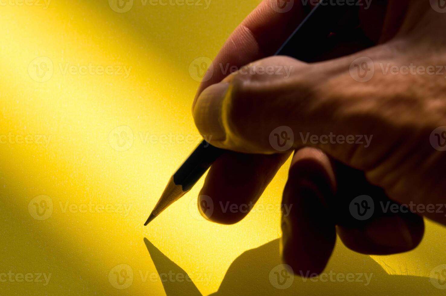 Human's hand holding pencil to write on the paper in shadow photo