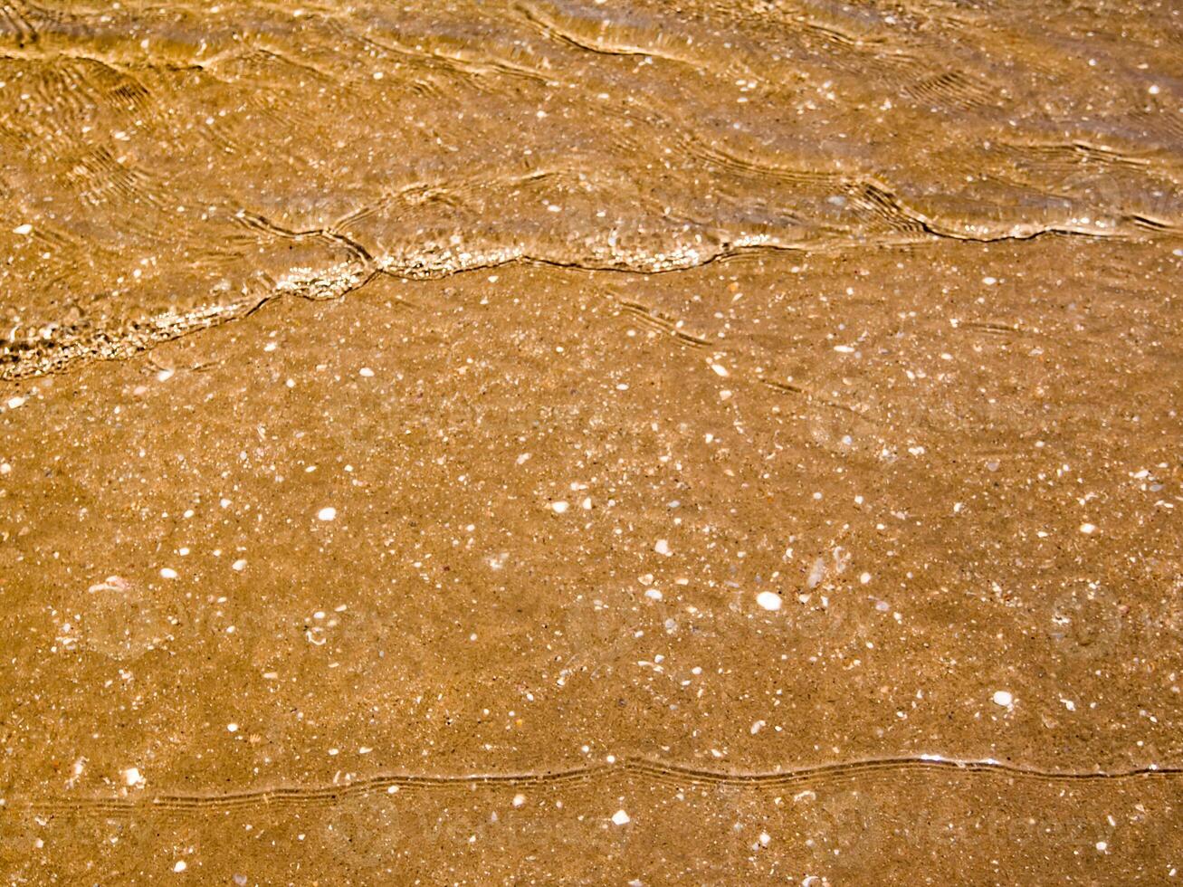 Light reflection on surface of movement sea on sand beach photo