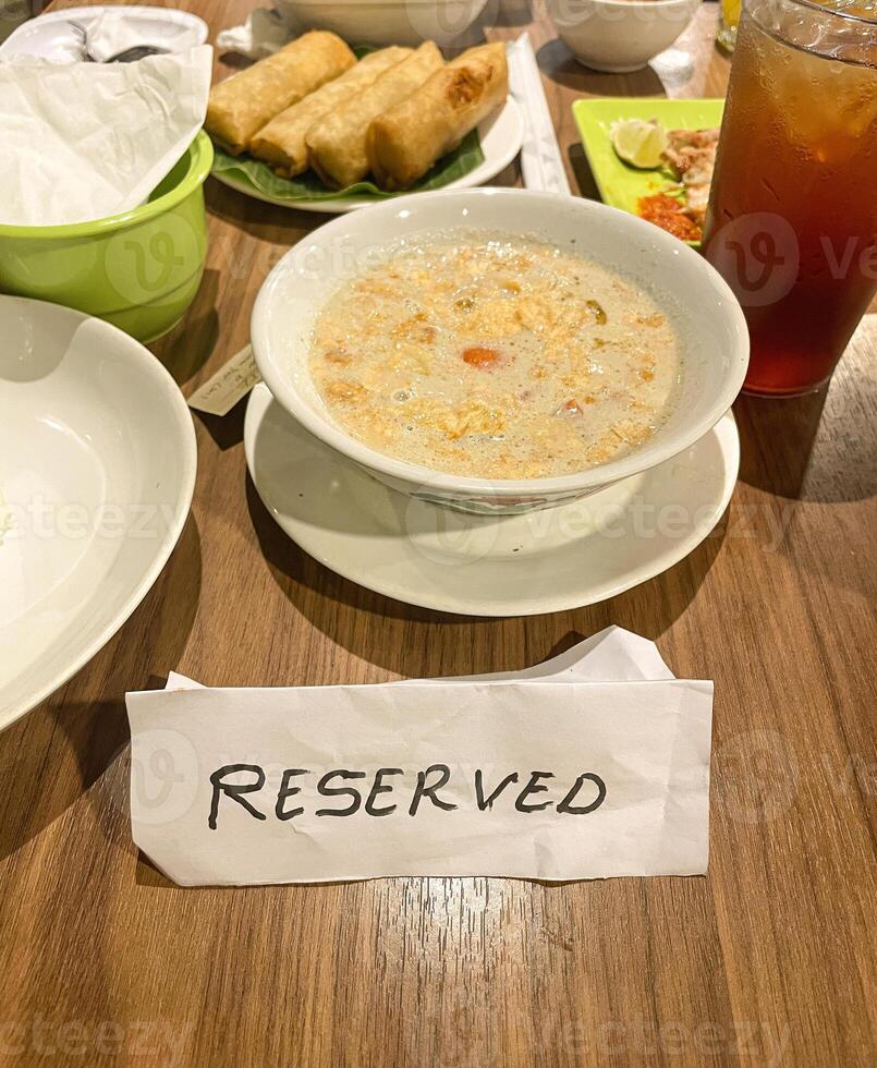 Reserved sign on table in restaurant with food served photo