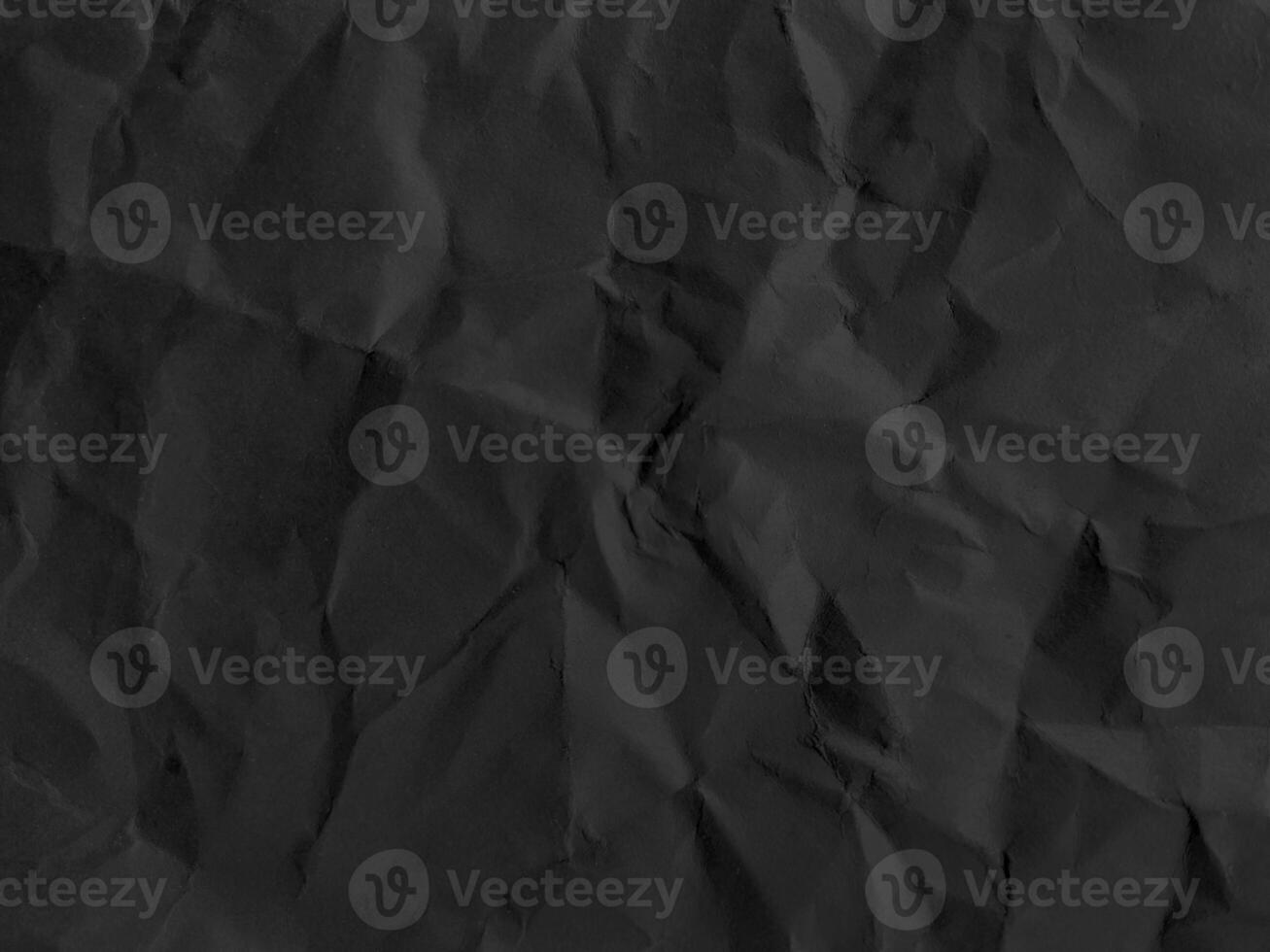 Black crumpled paper texture in low light background photo