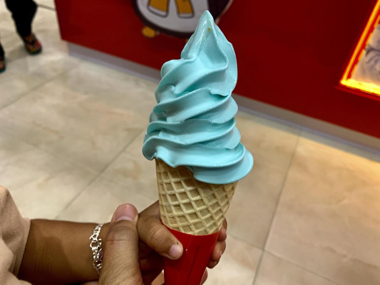 someone holding a large ice cream cone with blue icing photo