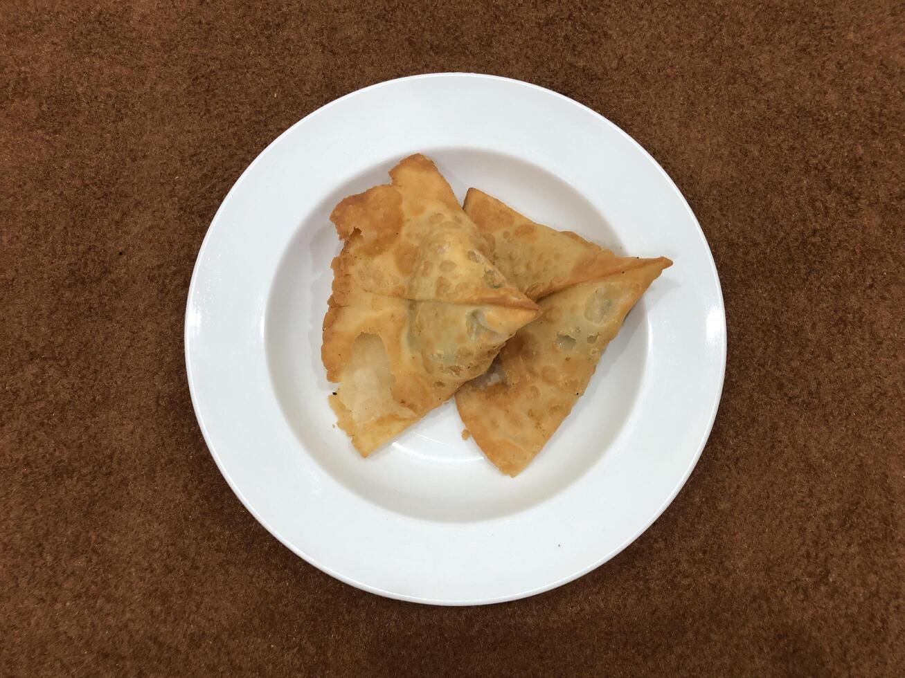 Fresh delicious crispy Two samosas on white Plate, top view, isolated photo