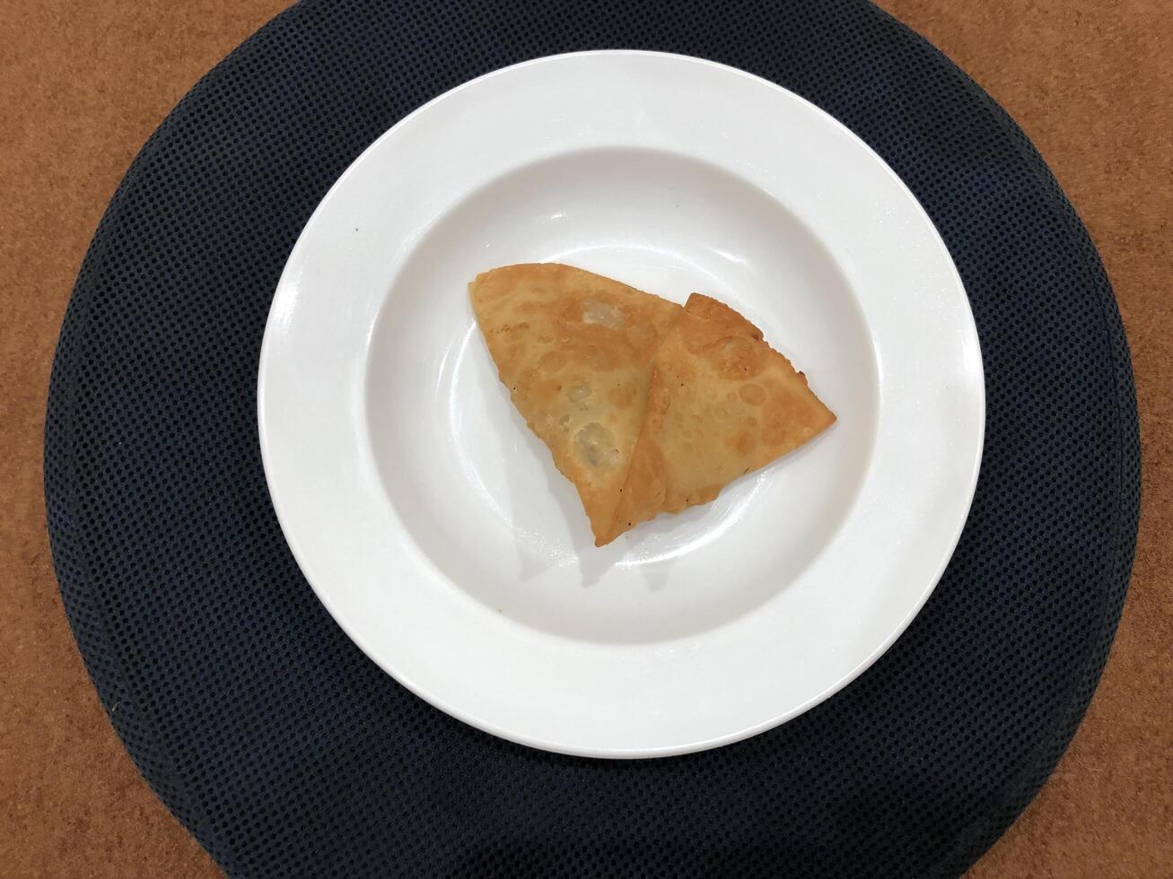 Fresh delicious crispy samosas on white Plate, top view, isolated photo