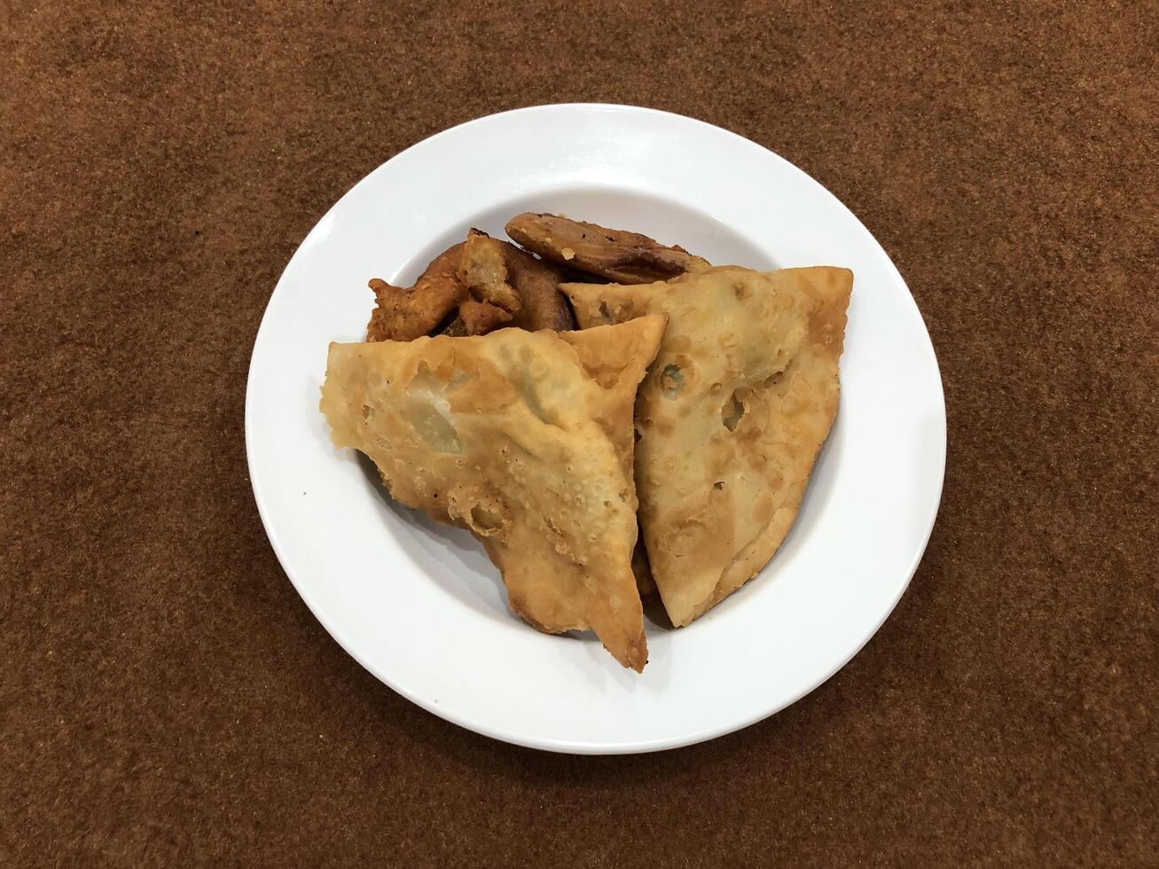 solated top view of qeema samosa and basin pakora in white plate, Popular indian or pakistani street food snack on white background, Diwali dinner or iftar meal. photo