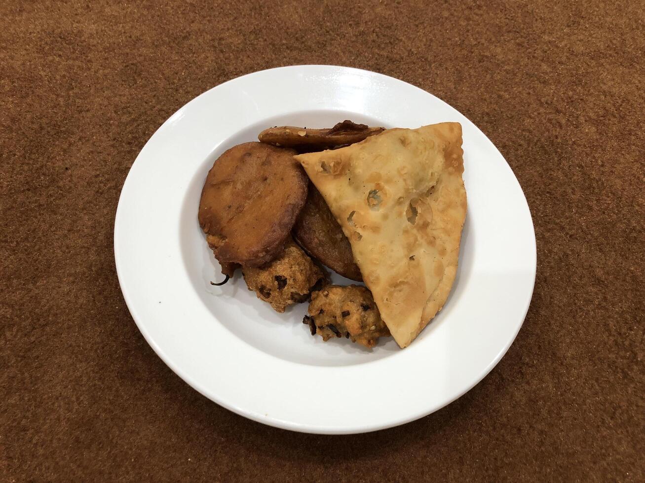 solated top view of qeema samosa and basin pakora in white plate, Popular indian or pakistani street food snack on white background, Diwali dinner or iftar meal. photo