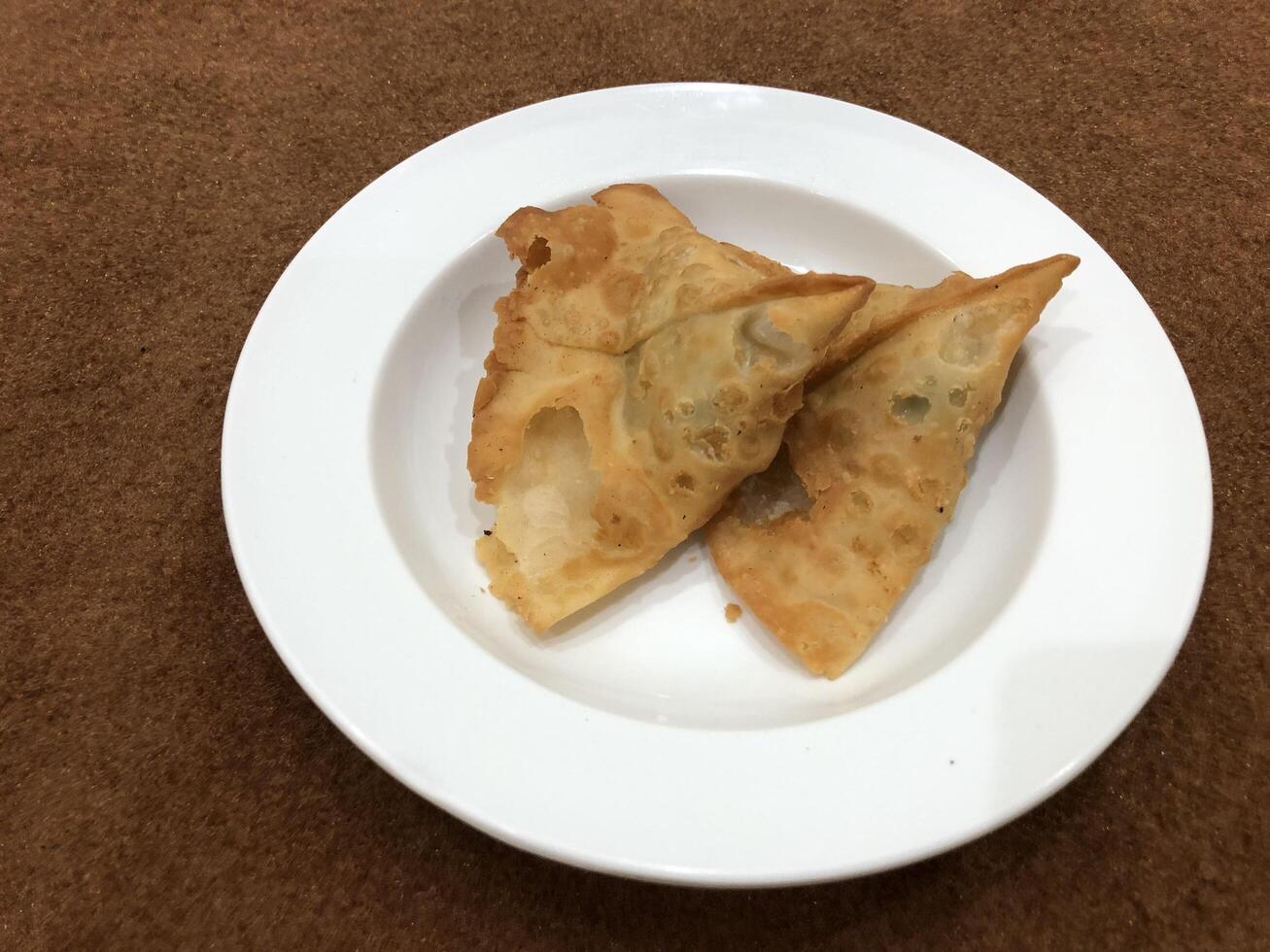 Fresh delicious crispy Two samosas on white Plate, top view, isolated photo