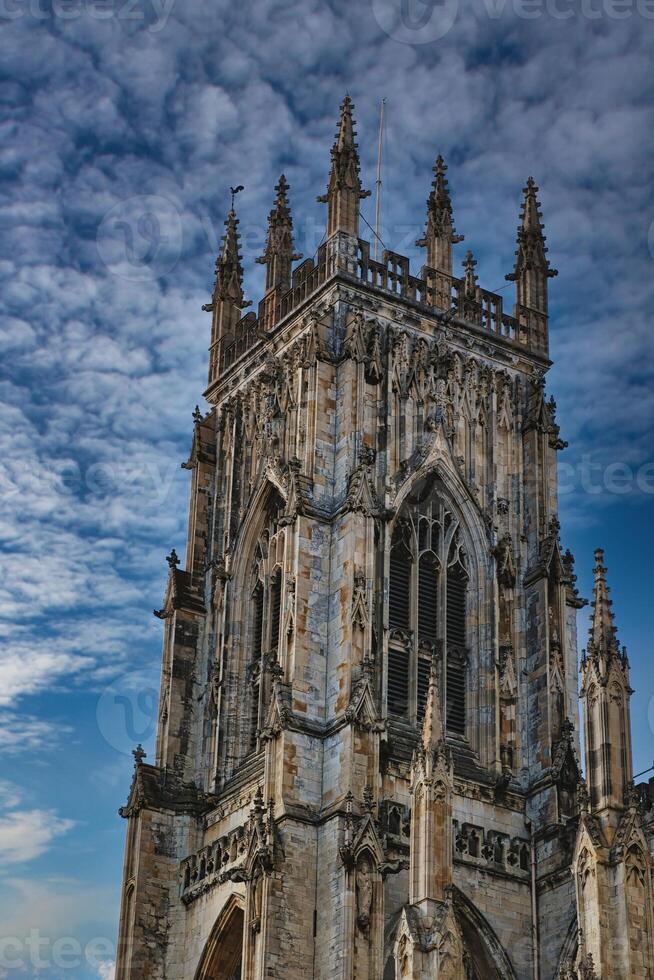 Gothic cathedral tower against a dramatic cloudy sky, showcasing intricate architectural details and spires, ideal for historical or religious themes in York, North Yorkshire, England. photo