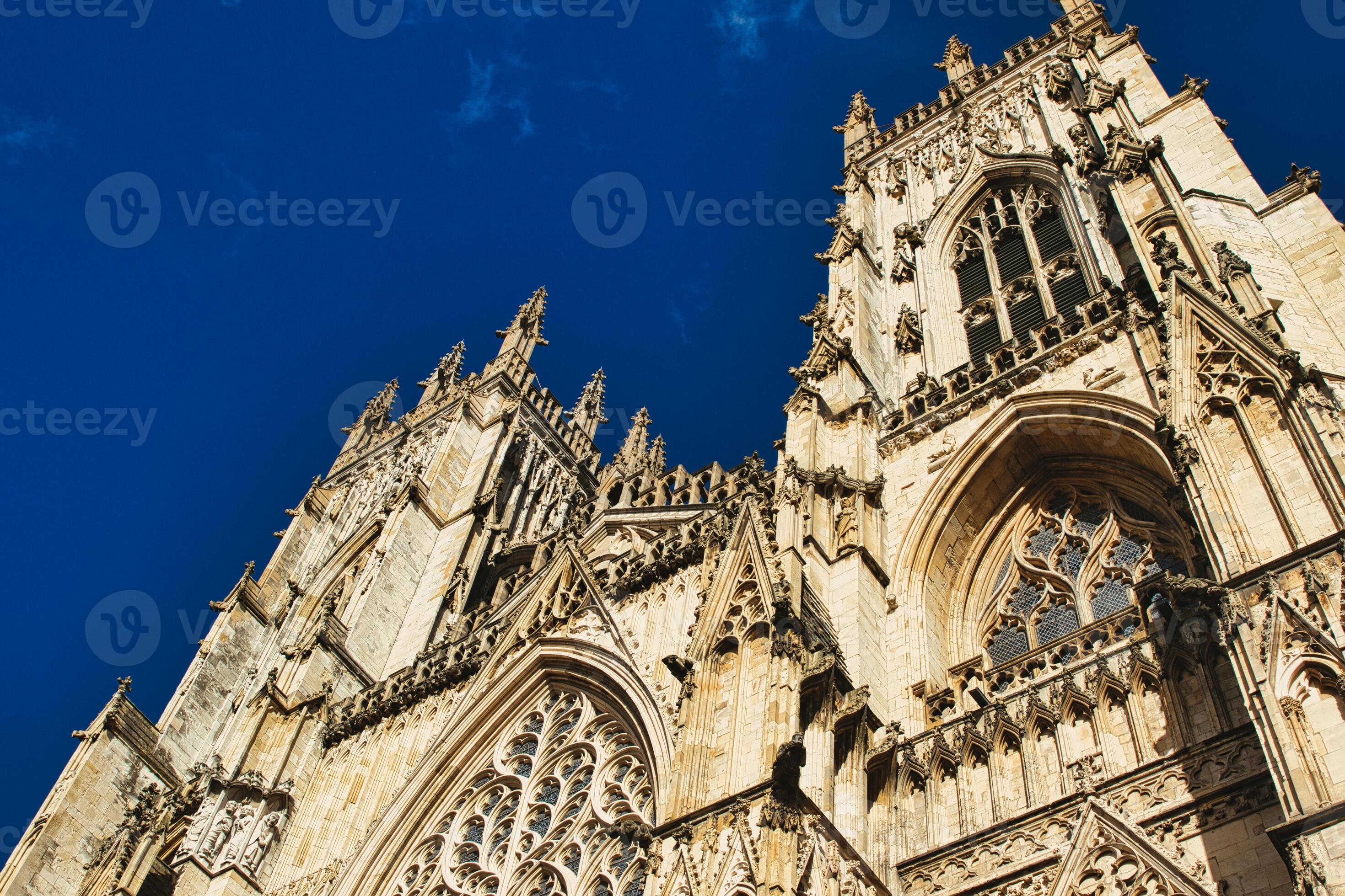 The ancient stone facade of Bangor Cathedral under a blue sky, showcasing its Gothic architecture.