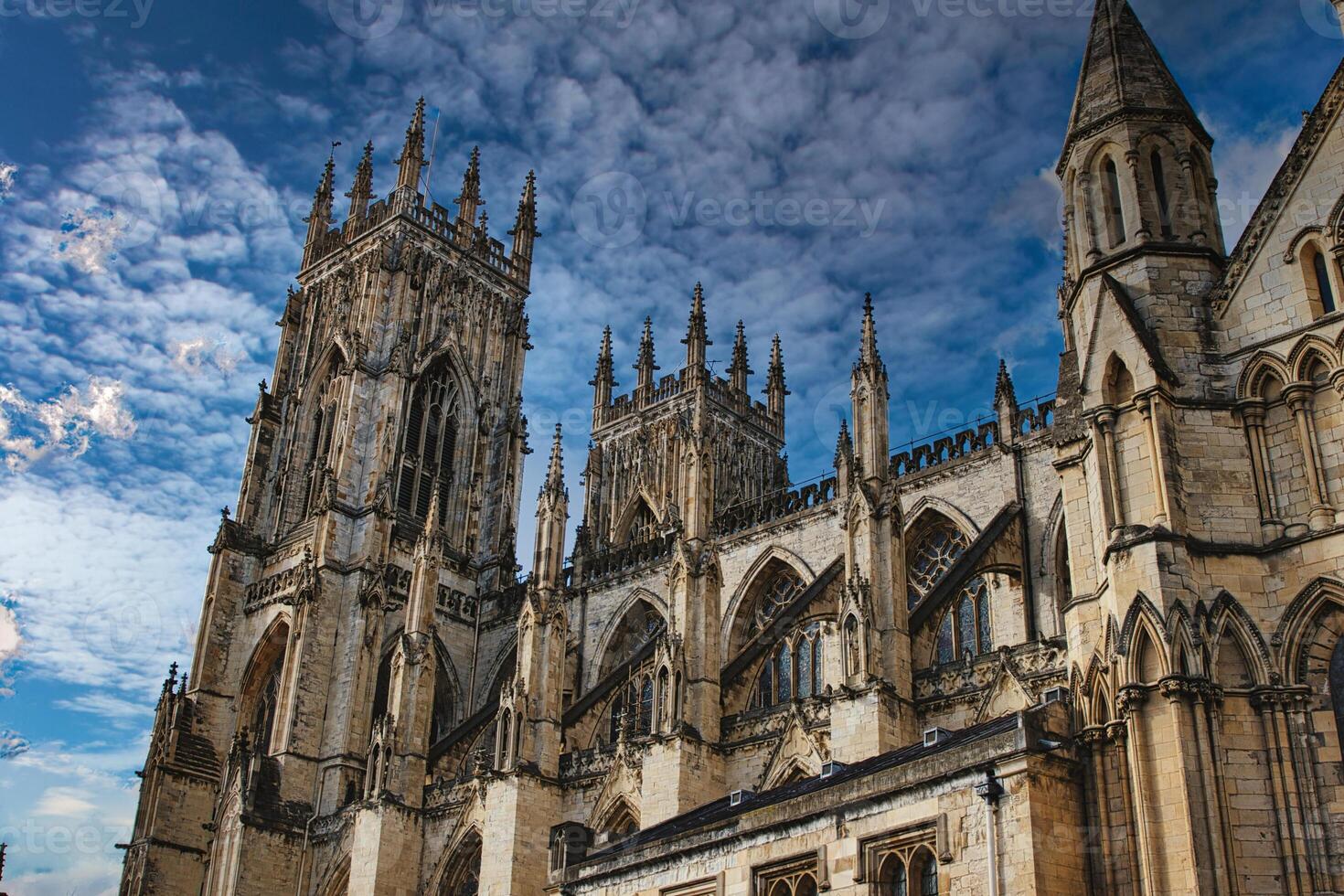 Gothic cathedral tower against a dramatic cloudy sky, showcasing intricate architectural details and spires, ideal for historical or religious themes in York, North Yorkshire, England. photo