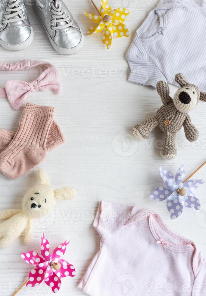 Baby clothes with knitted toys dog and rabbit, toy windmills and baby shoes and accessories. photo