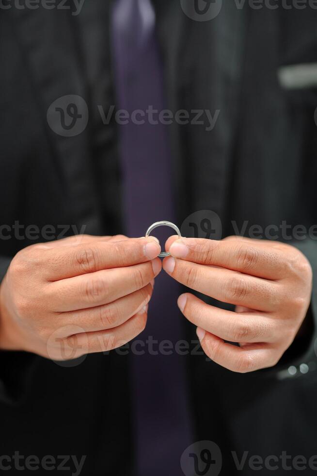 Wedding ring photo shoot concept a man wearing a formal black suit and purple tie is holding a wedding ring