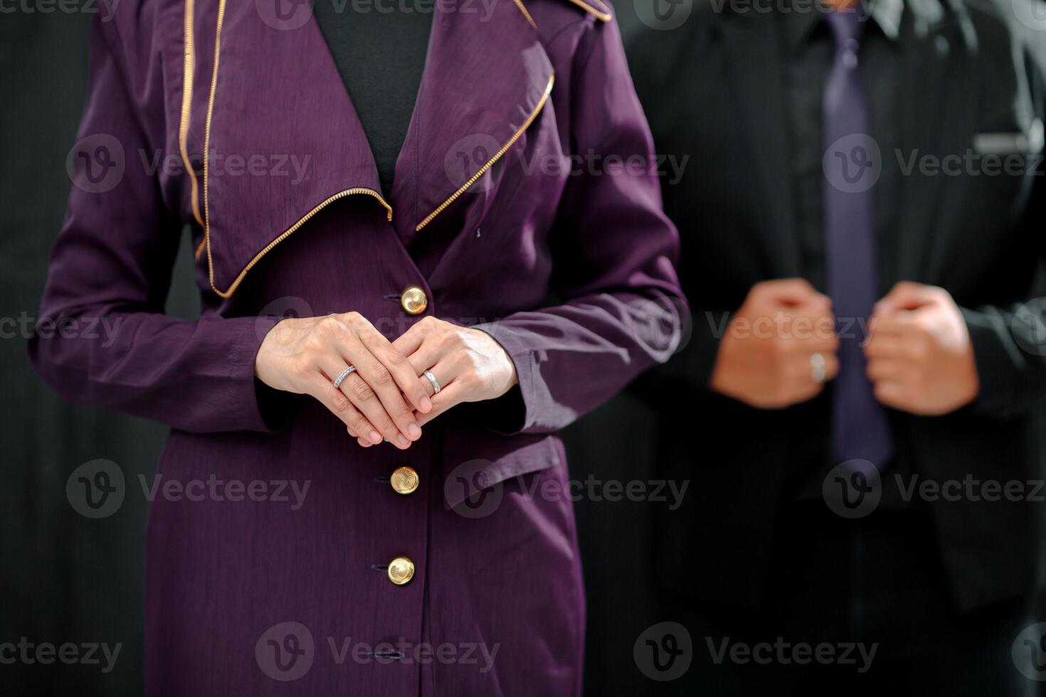 Wedding ring photo shoot concept a man wearing a formal black suit and purple tie and woman with purple suit is holding a wedding ring