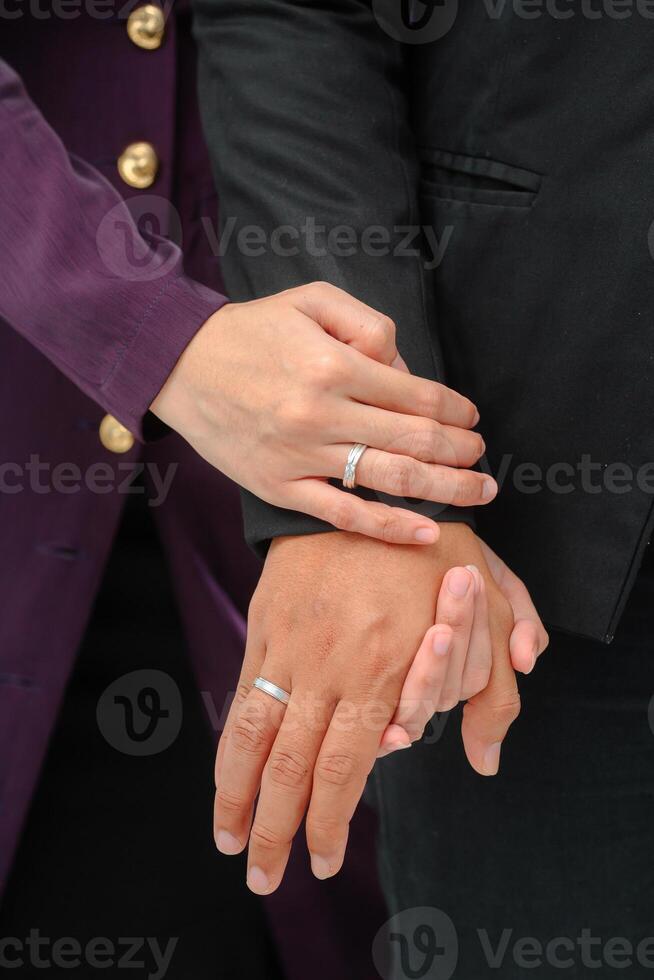 Wedding ring photo shoot concept a man wearing a formal black suit and purple tie is holding a wedding ring