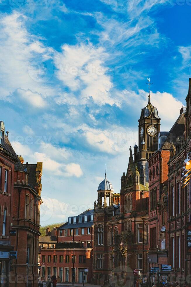 Vintage European architecture with a prominent clock tower under a vibrant blue sky with wispy clouds, capturing the essence of historic urban charm in York, North Yorkshire, England. photo