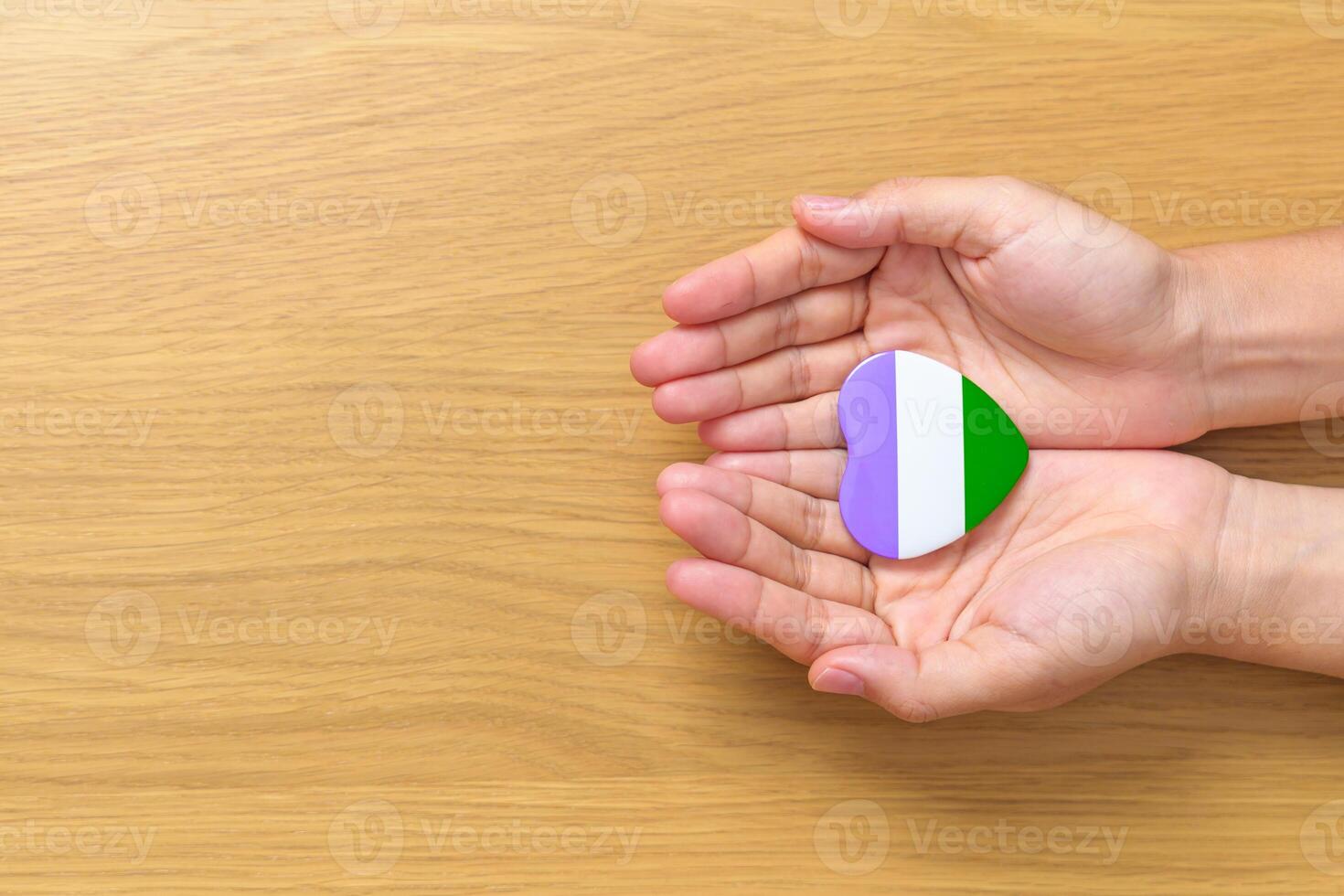 Queer Pride Day and LGBT pride month concept. hand holding purple, white and green heart shape for Lesbian, Gay, Bisexual, Transgender, genderqueer and Pansexual community photo