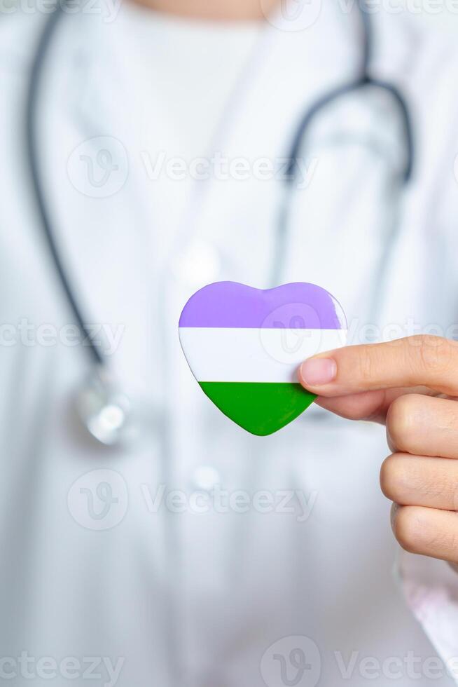 Queer Pride Day and LGBT pride month concept. Doctor hand holding purple, white and green heart shape with Stethoscope for Lesbian, Gay, Bisexual, Transgender, genderqueer and Pansexual community photo