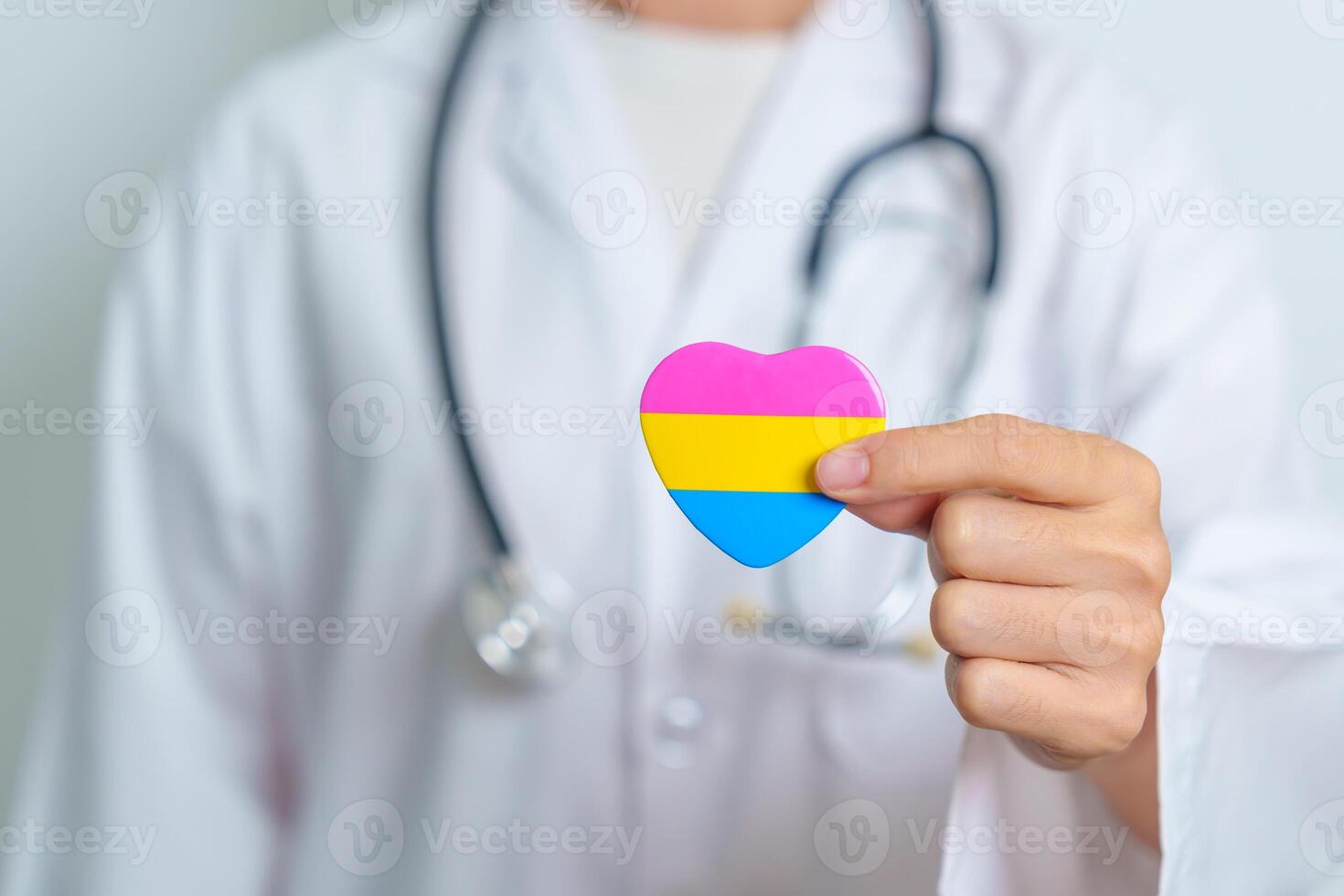 Pansexual Pride Day and LGBT pride month concept. Doctor hand holding pink, yellow and blue heart shape for Lesbian, Gay, Bisexual, Transgender, Queer and Pansexual community photo