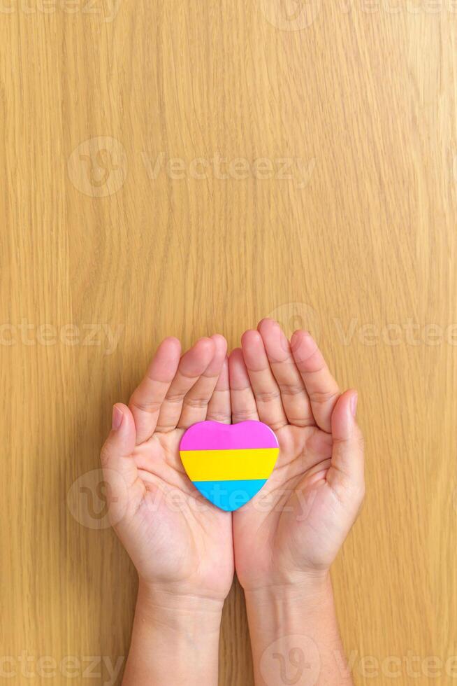 Pansexual Pride Day and LGBT pride month concept. hand holding pink, yellow and blue heart shape for Lesbian, Gay, Bisexual, Transgender, Queer and Pansexual community photo