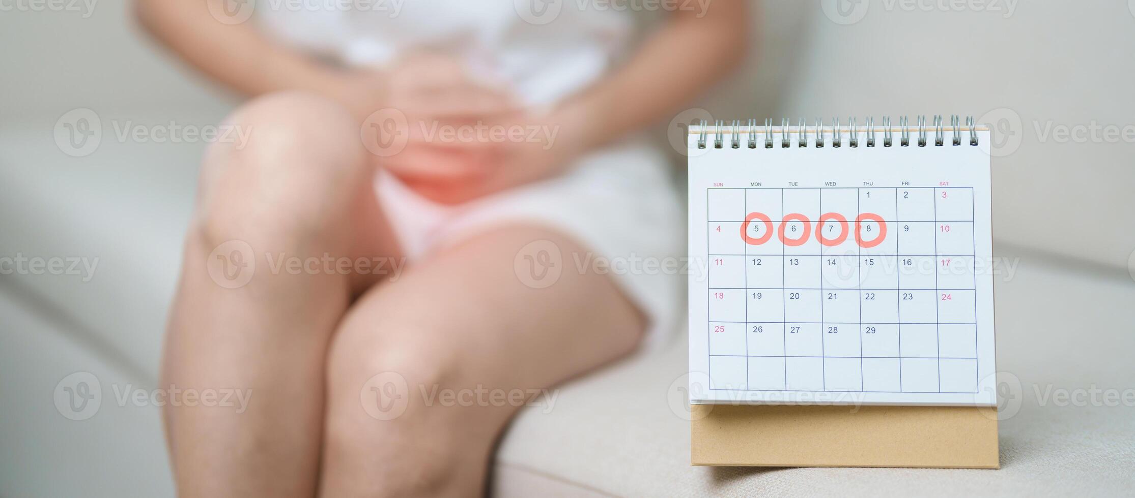 Menstruation period cycle of monthly and Stomachache concepts. woman having abdomen pain with calendar, illness female suffer from premenstrual ache and body Health problem on sofa at home photo
