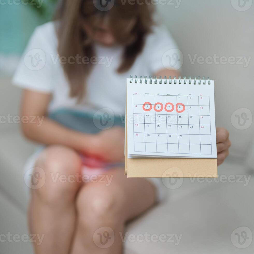 Menstruation period cycle of monthly and Stomachache concepts. woman having abdomen pain with hot water bottle and calendar, illness female suffer from premenstrual ache and body Health problem photo