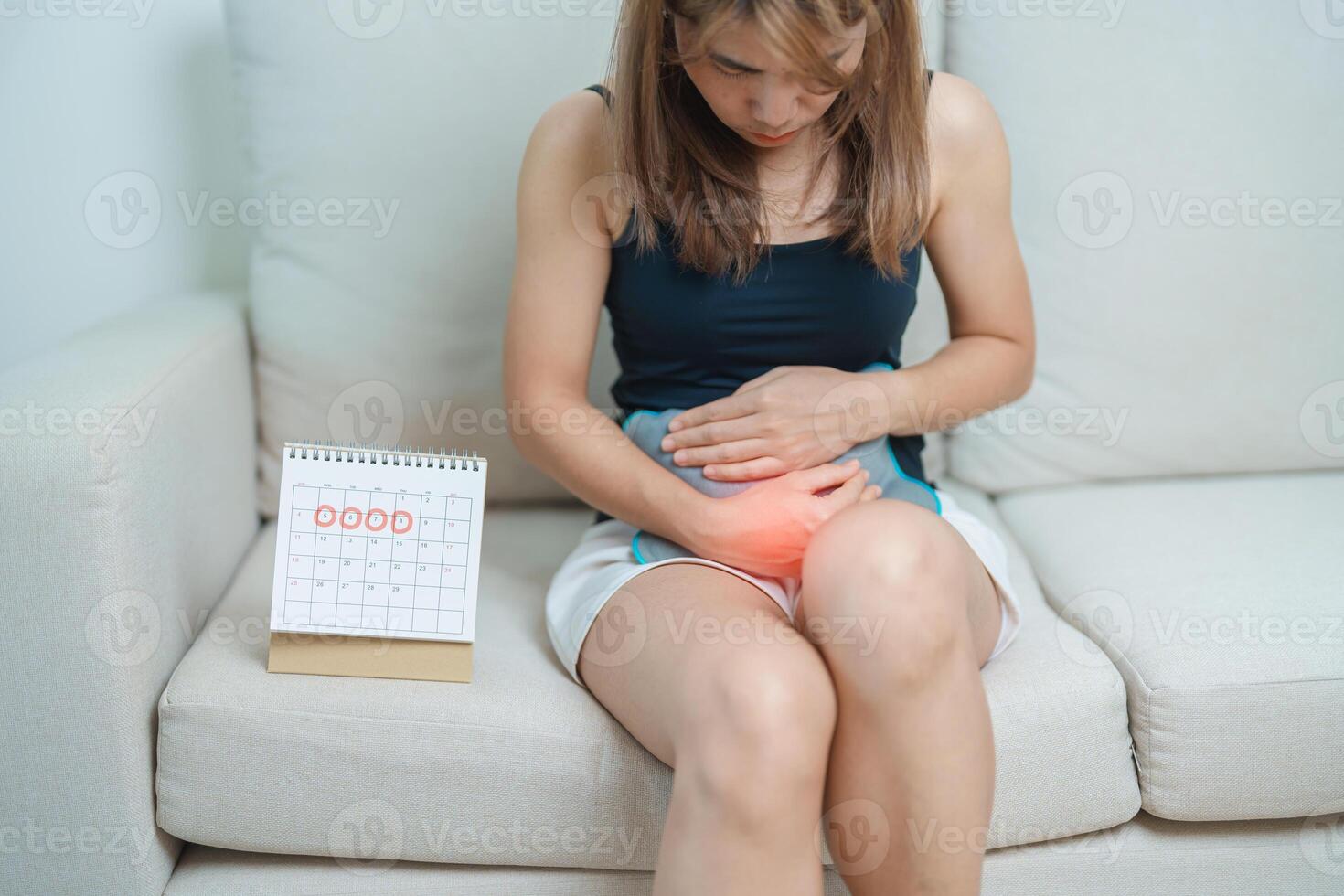 Menstruation period cycle of monthly and Stomachache concepts. woman having abdomen pain with hot water bottle and calendar, illness female suffer from premenstrual ache and body Health problem photo