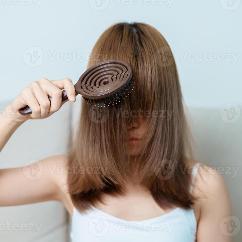 Hair care and Daily routine concepts. asian woman holding holding comb and hair brushing in the morning, young female hold hairbrush with long straight hair at home photo