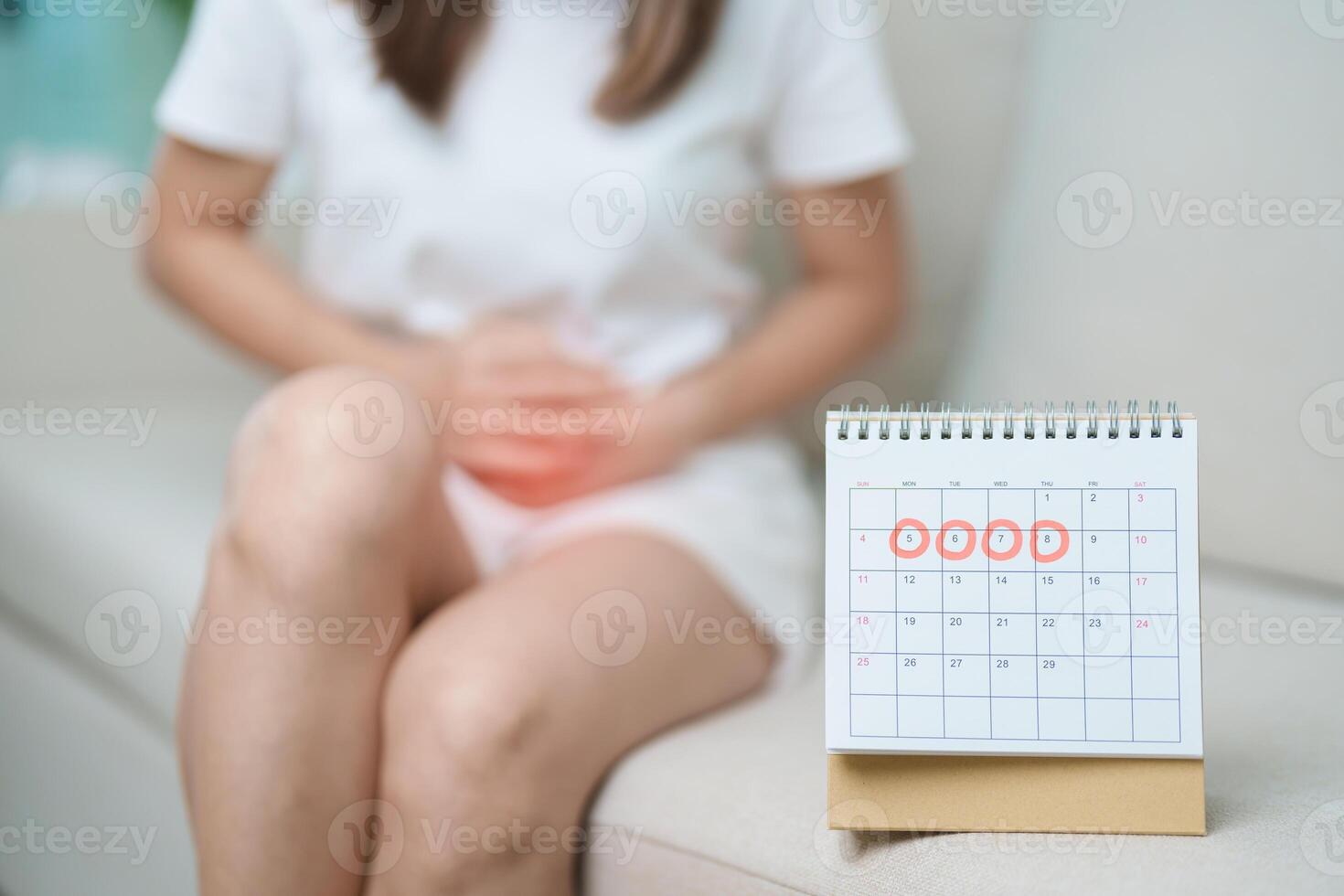 Menstruation period cycle of monthly and Stomachache concepts. woman having abdomen pain with calendar, illness female suffer from premenstrual ache and body Health problem on sofa at home photo