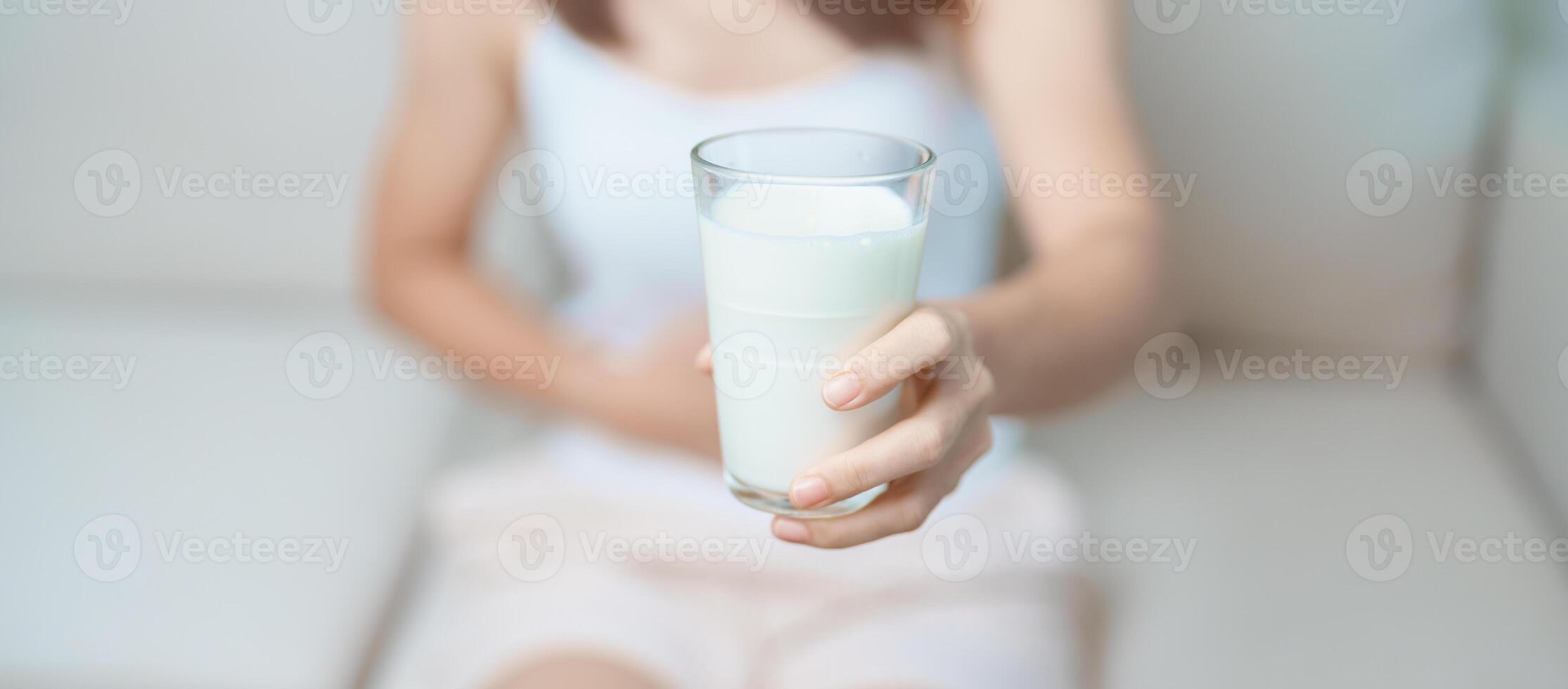 Lactose intolerance and Milk allergy concept. woman hold Milk glass and having abdominal cramps and pain when drink Cow Milk. Symptom stomach ache, Dairy intolerant, Nausea, Bloating, Gas and Diarrhea photo