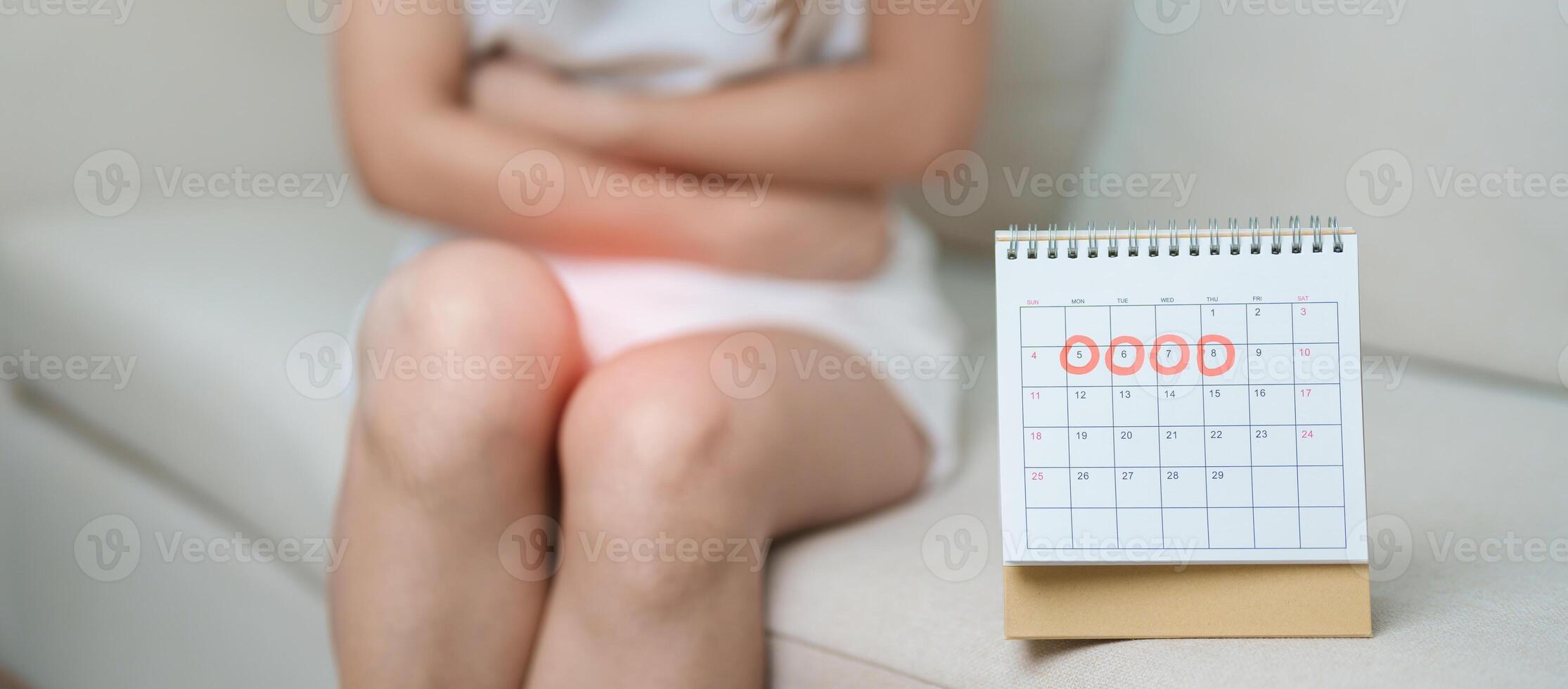 Menstruation period cycle of monthly and Stomachache concepts. woman having abdomen pain with calendar, illness female suffer from premenstrual ache and body Health problem on sofa at home photo