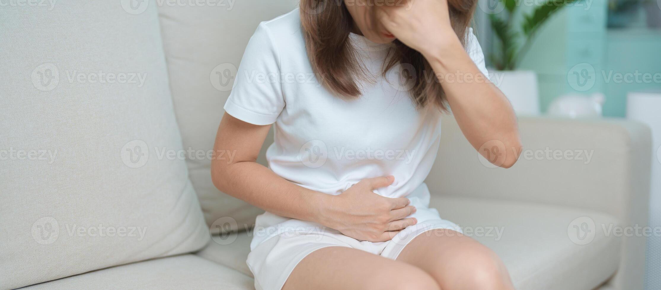 woman having abdomen ache due to Stomach pain, digestion with constipation or Diarrhea from food poisoning, female problem and Endometriosis, Hysterectomy, Stomachache and Menstrual on sofa at home photo